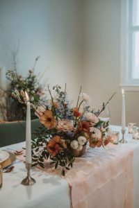 Spring centrepiece with butterfly ranunculus, ranunculus, pussy willows, delphinium, lisianthus, and branches in a blush, burgundy, and blue palette | Montreal wedding florist