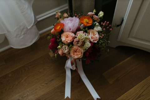Spring bouquet with coral, apricot, pink, and orange tied in garden-gathered style tied with flowing satin ribbons | Flourish & Knot | Montreal wedding florist | Photo by Naomie Houle