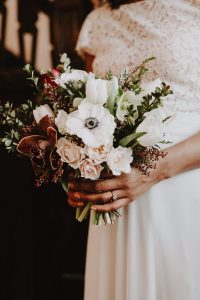 Winter wedding bouquet of anemone, tulips, hellebore, spray roses, and cymbidium orchid | Burgundy, blush, and white winter wedding bouquet | Florals by Flourish & Knot | Photography by Photographie M'Vivre | Maison Trestler | Gown by Robelie | Makeup by Chrom Artistry