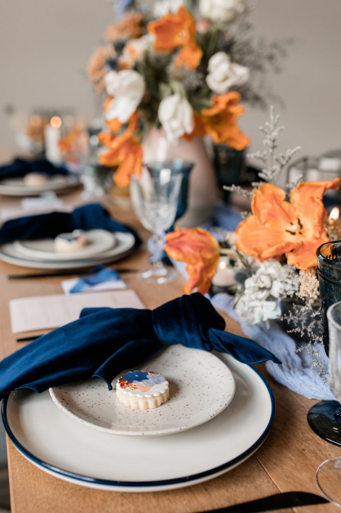 Terracotta, orange, and blue wedding palette | Wedding centrepiece with tulips and velvet napkins | Flourish & Knot