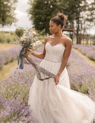 Bride holding bouquet in lavender field with trailing silk ribbons