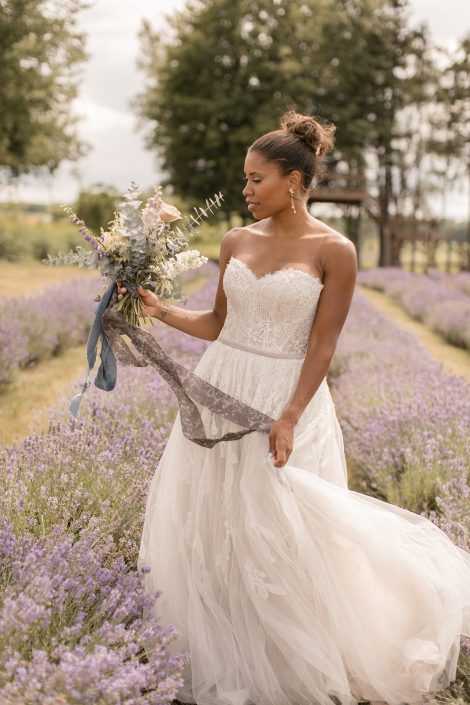 Bride holding bouquet in lavender field with trailing silk ribbons