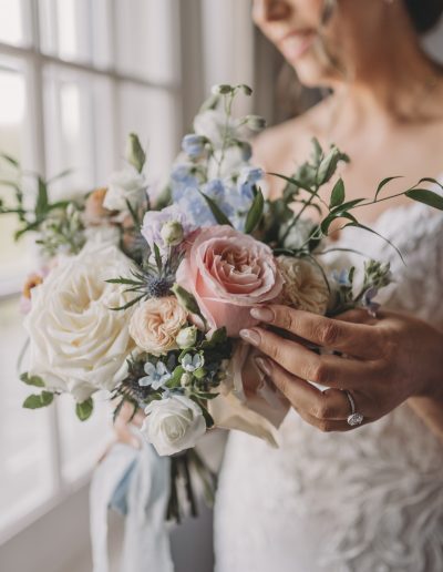 Bride touching peach rose in blush and pale blue bridal bouquet | Flourish & Knot