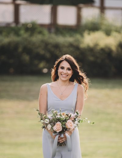 Bridesmaid in dusty blue dress with peach and blue bouquet
