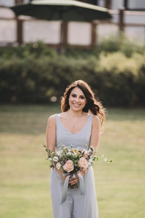 Bridesmaid in dusty blue dress with peach and blue bouquet