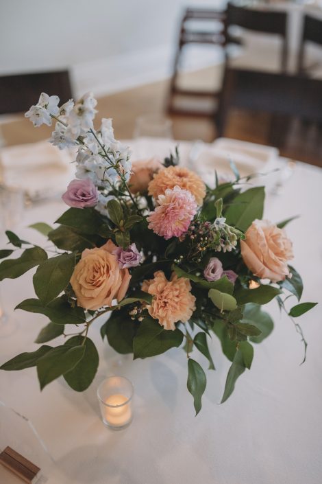 Peach and pale blue compote centrepiece with roses and delphinium