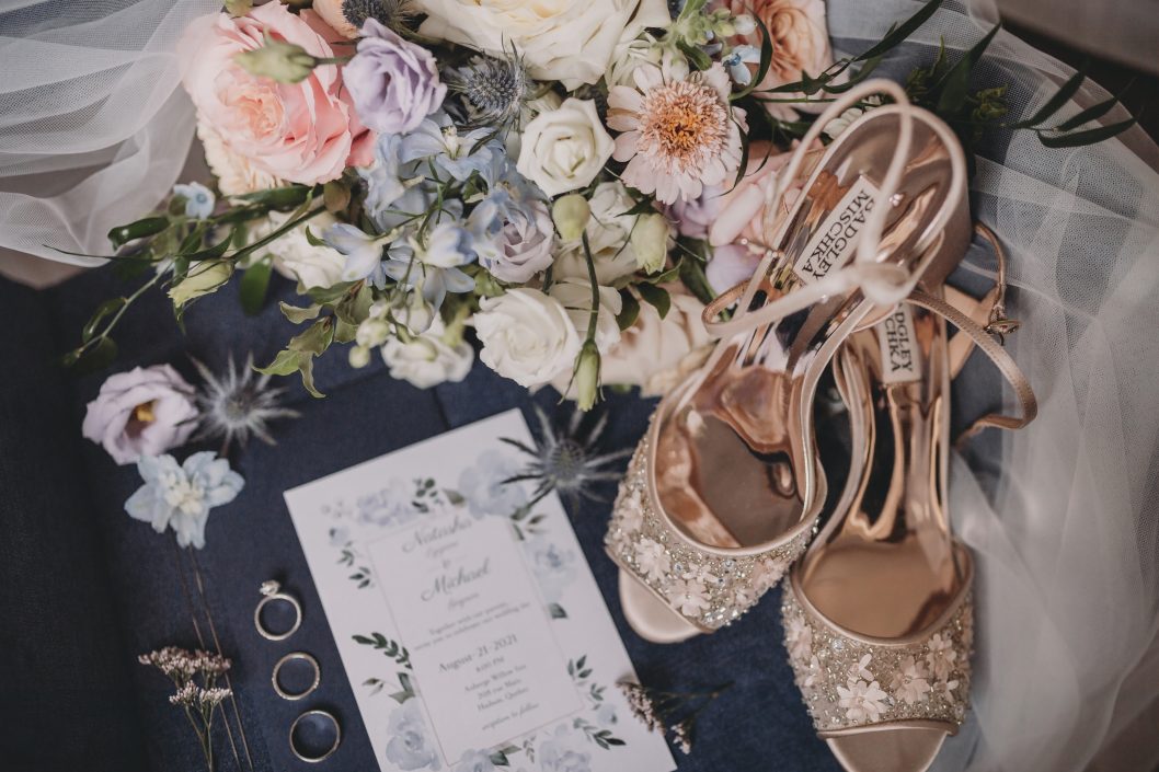 Flat lay of bridal bouquet in peach and pale blue with blush shoes and invitation suite