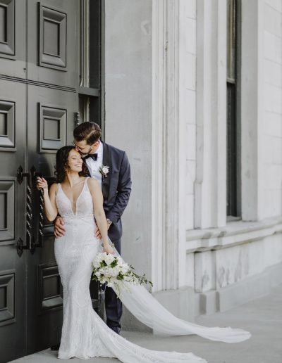 Groom kissing top of bride's head with classic white bouquet in Old Montreal