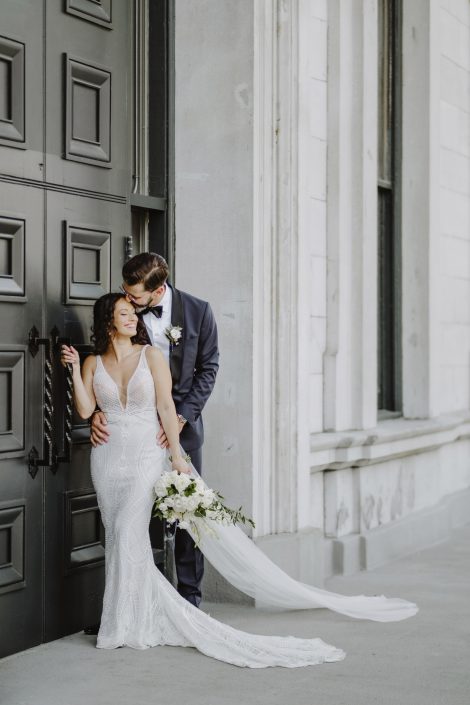 Groom kissing top of bride's head with classic white bouquet in Old Montreal