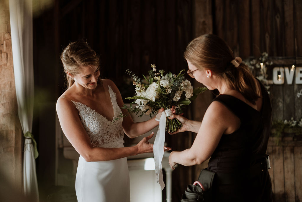 Bride receiving and examining her bouquet, tied with a silk ribbon