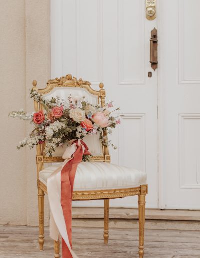 Peach coral pink and blue spring bridal bouquet with silk ribbon on vintage gold chair | Kerstin Hahn Photography | Flourish & Knot