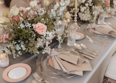 Spring floral centrepiece in pink peach and blue palette with silver place setting with gold-foiled ribbon place marker and lily of the valley | Kerstin Hahn Photography | Flourish & Knot