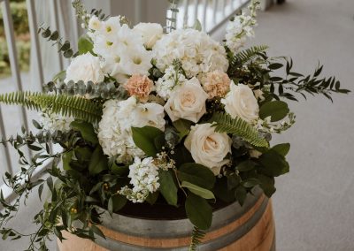 Classic white, blush, and peach wine barrel floral arrangement