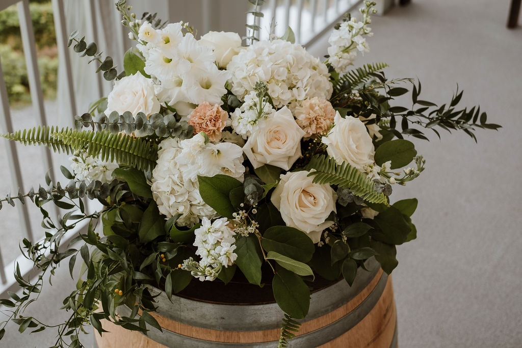 Classic white, blush, and peach wine barrel floral arrangement