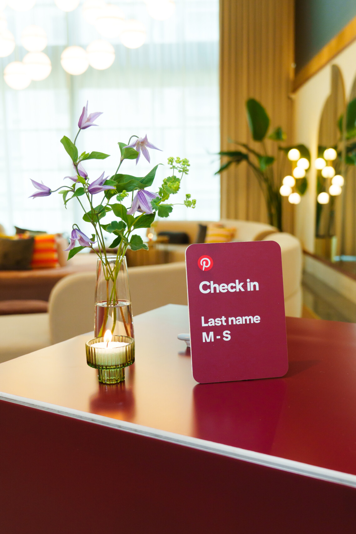 Bespoke floral vase arrangement on a deep red Pinterest corporate event check-in desk designed by Flourish and Knot.