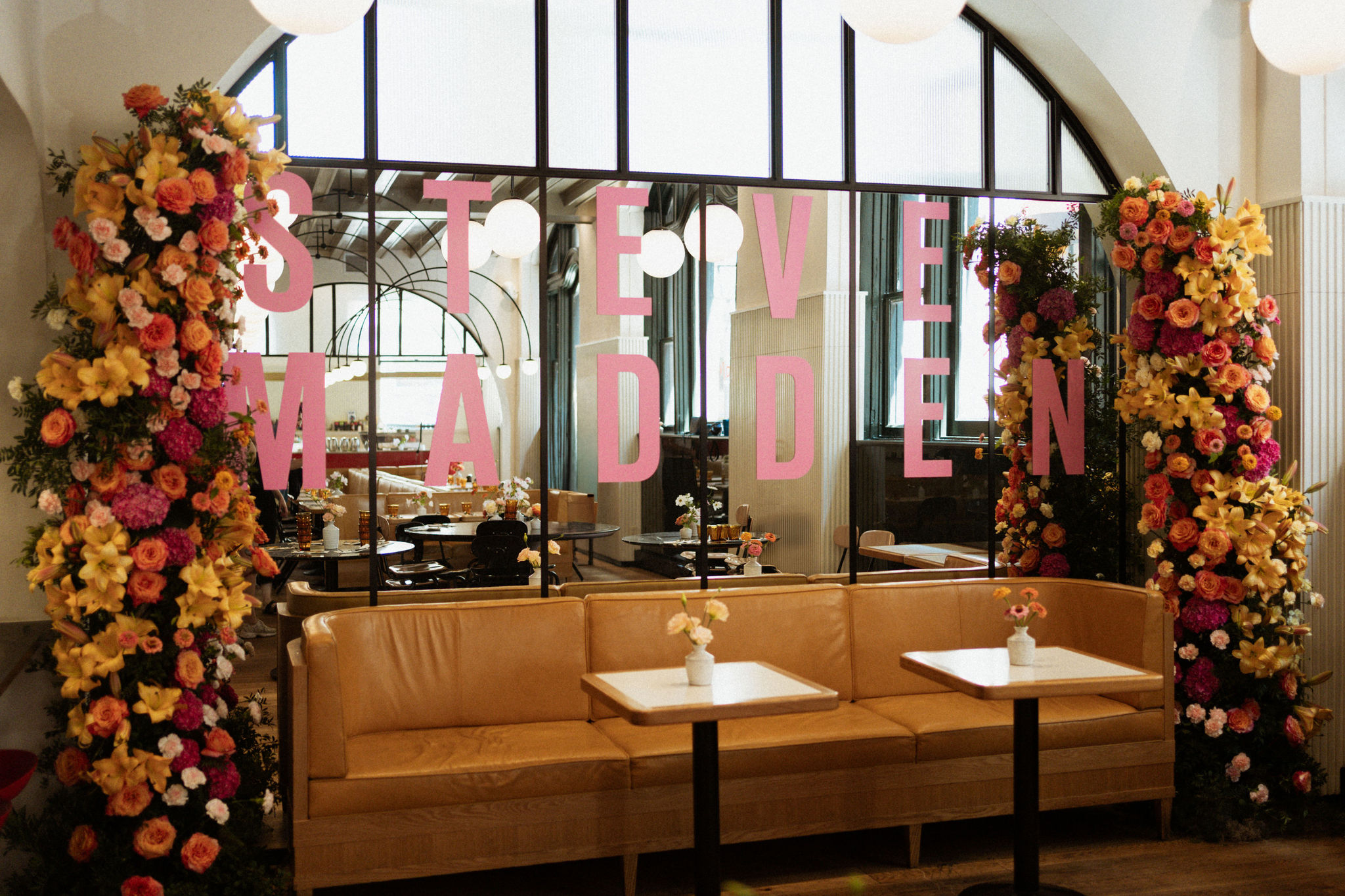 Large-scale vibrant floral pillars framing a branded Steve Madden window display at a luxury fashion launch event in Montreal